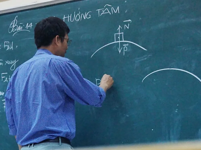 Un professeur qui écrit à la craie sur un tableau vert devant sa classe